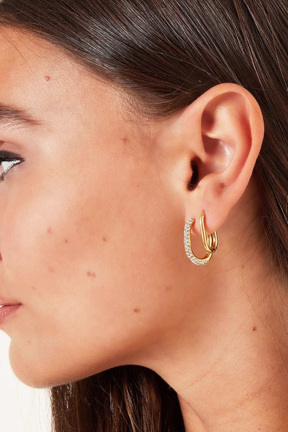 Oorbellen | Ovale Hoepels van Louxx the brand, close-up van gouden hoepels met een glinsterende afwerking, gestyled voor een trendy look.