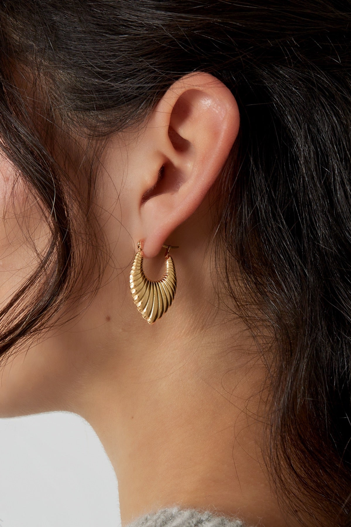 Model draagt de Oorbellen | Crush van Louxx the brand. Gouden oorringen met een elegante, gedetailleerde afwerking, zichtbaar in het oor.