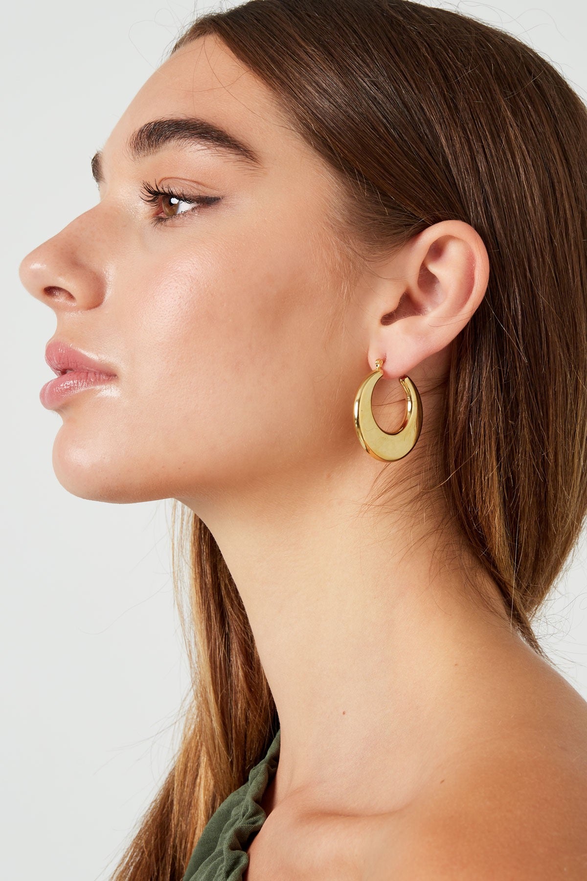 Zijaanzicht van een vrouw met Louxx the brand Oorbellen | Rond, een prachtige gouden hoop die elegant langs de nek valt.