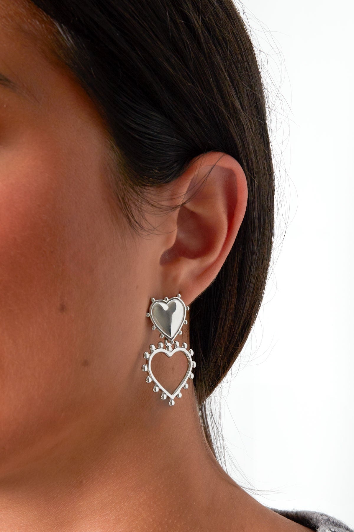 Oorbellen | Hart van Louxx the brand. Dichtbij opname van een model met de zilveren hartvormige oorbellen, die elegant en trendy zijn. Ideaal voor een feestelijke look!