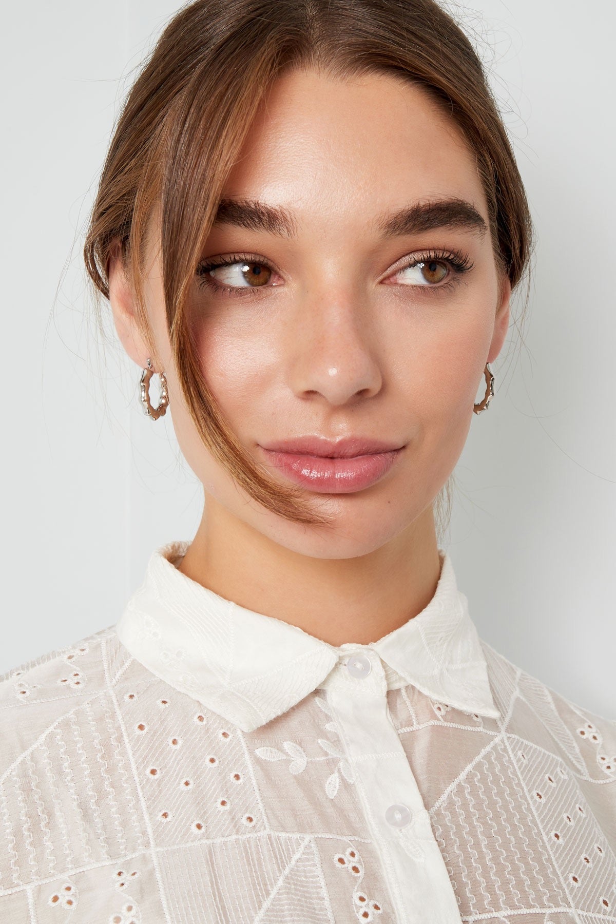 Close-up van een vrouw met zilveren oorbellen van Louxx the brand, Oorbellen | Aestheti. De oorbellen stralen luxe en stijl uit, perfect voor elke gelegenheid.