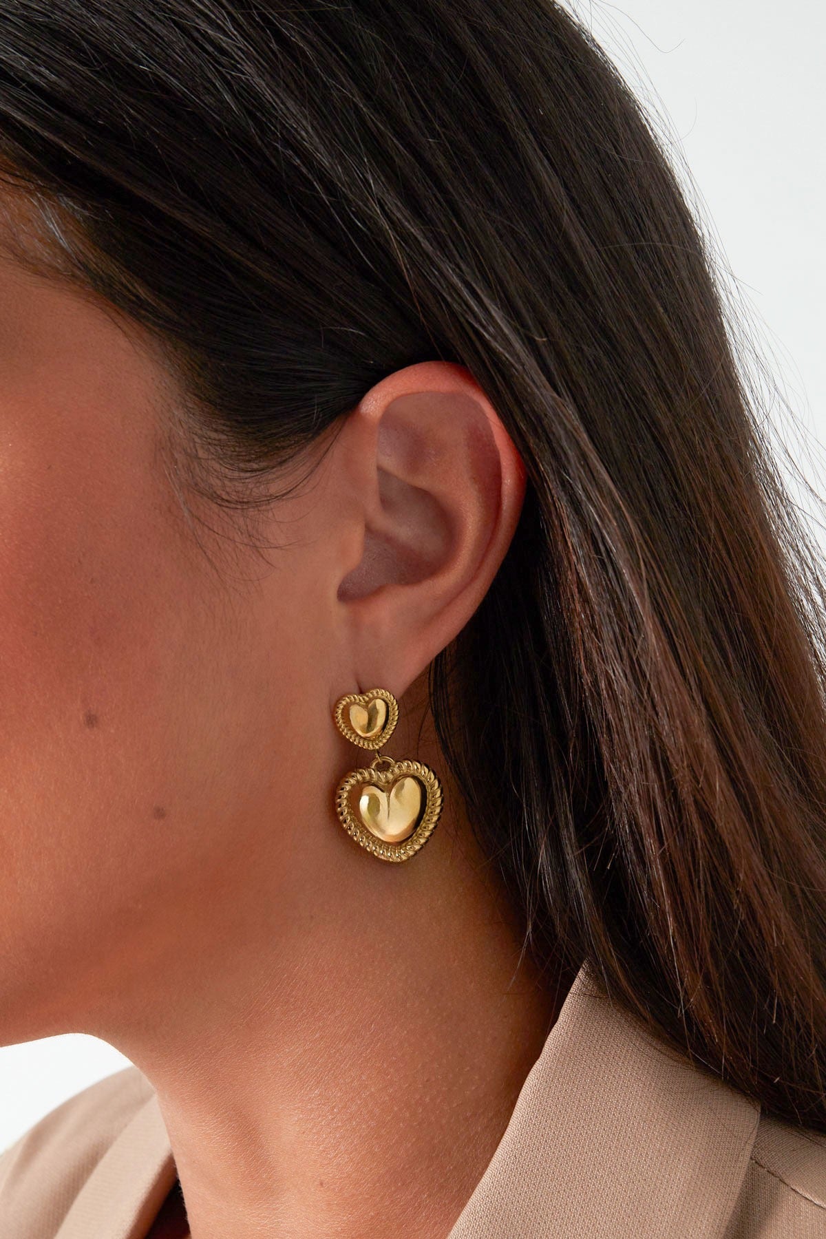 Een model dat gouden hart oorbellen van Louxx the brand draagt, waarmee een stijlvolle look wordt gecreƫerd. Prachtige gouden hart oorbellen.