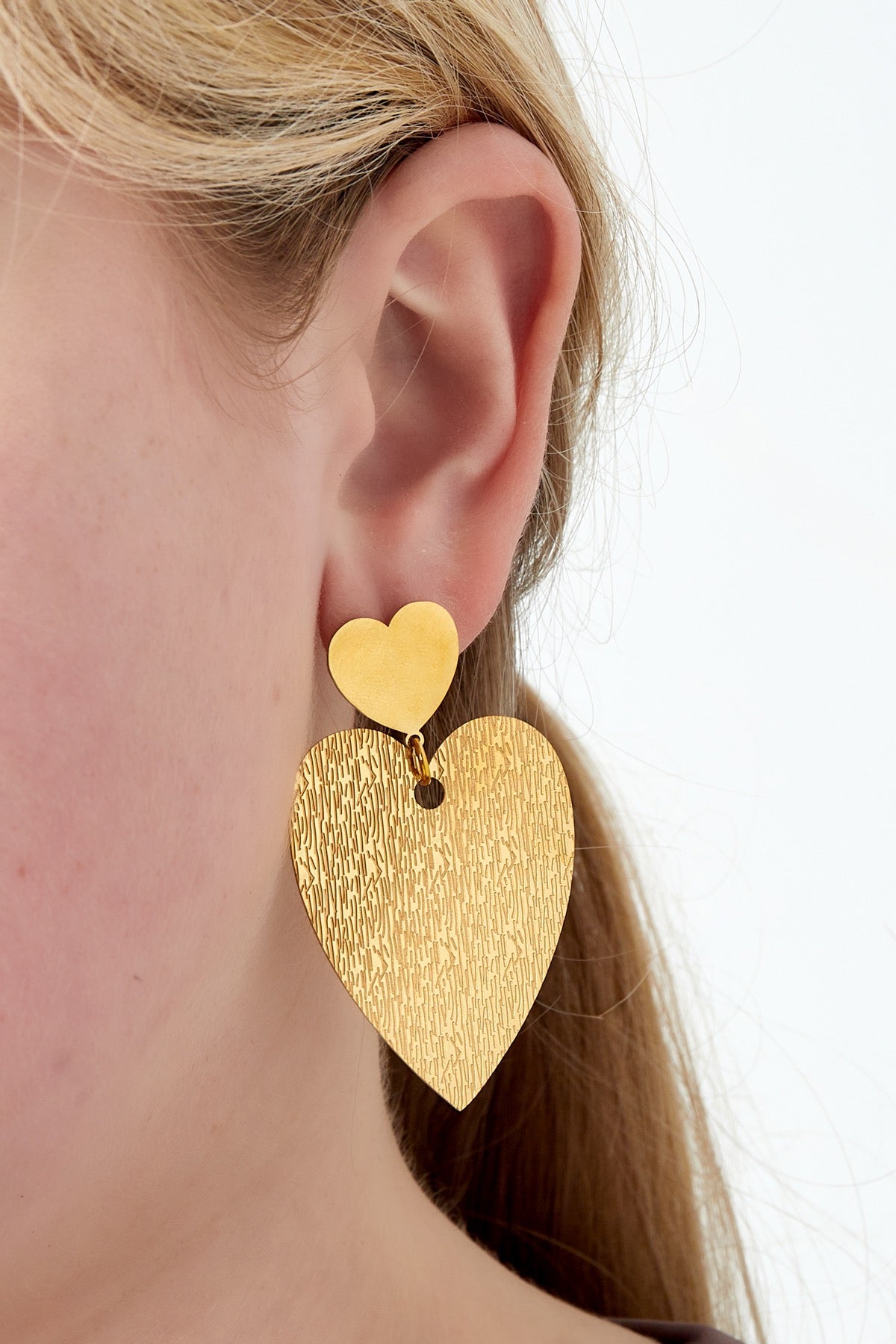 Close-up van gouden hart oorbellen van Louxx the brand. De unieke textuur en liefdevolle vorm maken ze een must-have.