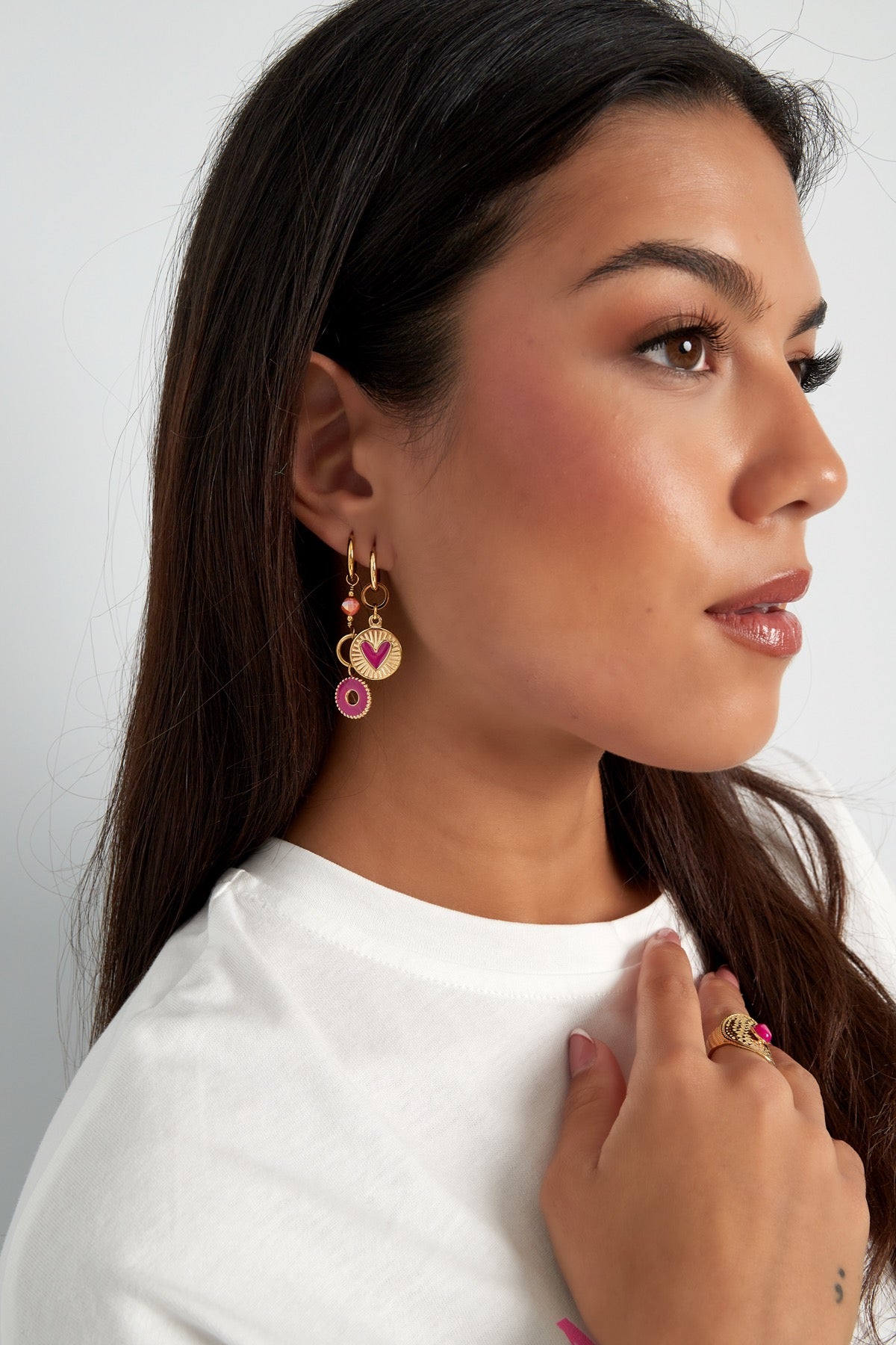 Oorbellen | Hart van Louxx the brand, een model met een casual outfit dat deze gouden oorbellen met hartjes toont, ideaal voor een dagelijkse look.