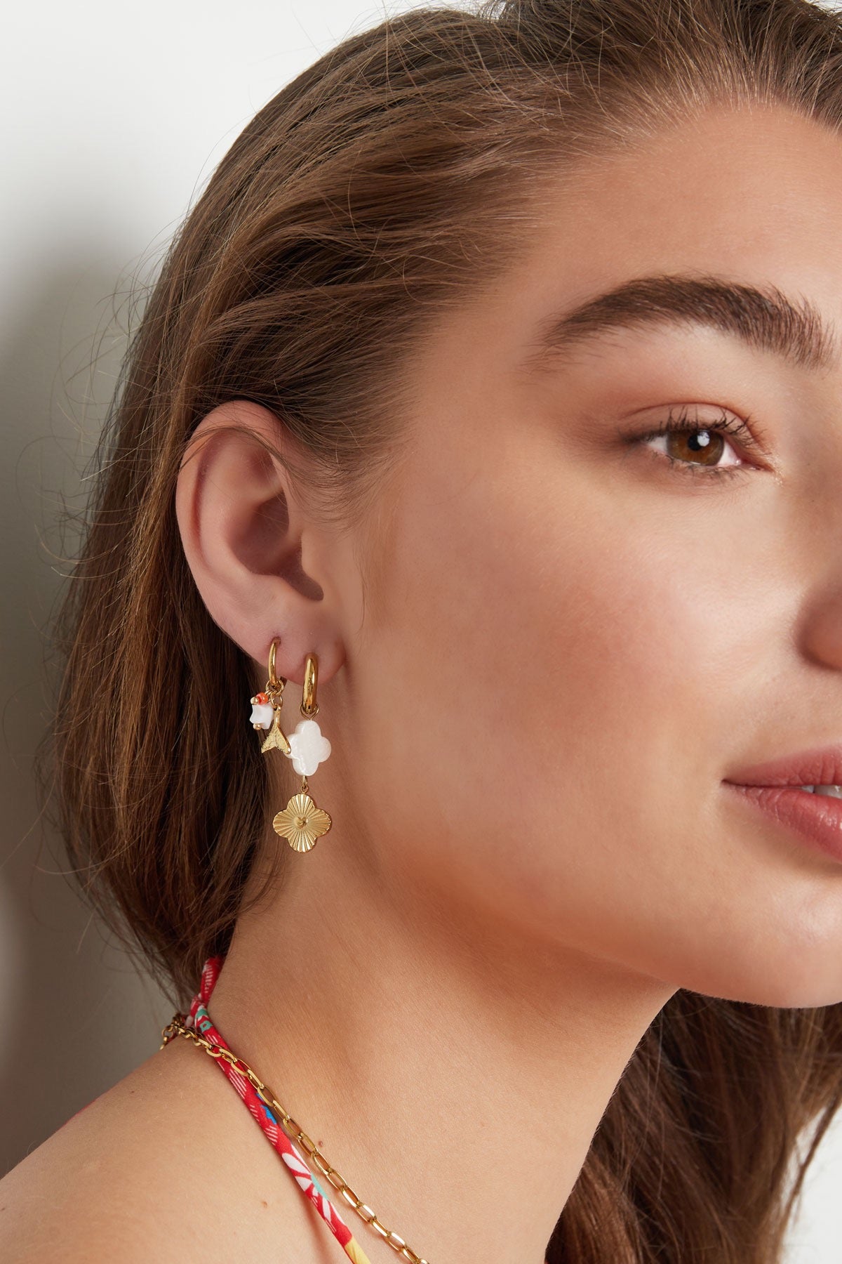 Oorbellen | Vin van Louxx the brand, draag deze stijlvolle gouden oorbellen met een delicate ster en bloem detail, ideaal voor elke gelegenheid.