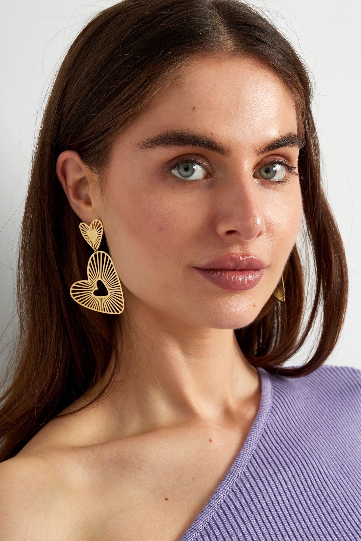 Close-up van luxe gouden hartoorbellen met een luchtig en modern design, ideaal voor een modieuze uitstraling.