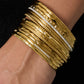 Goudkleurige bangle met strass gecombineerd met andere armbanden