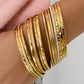 Glinsterende goudkleurige bangle gecombineerd met andere bangles om de pols